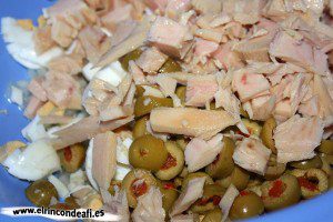 Ensaladilla rusa, desmenuzar el atún, el huevo y las aceitunas