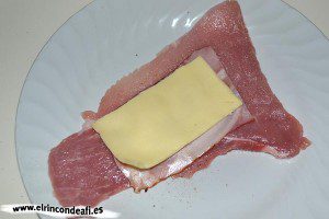 Enrolladitos de cerdo con bacon y queso, poner media loncha de queso