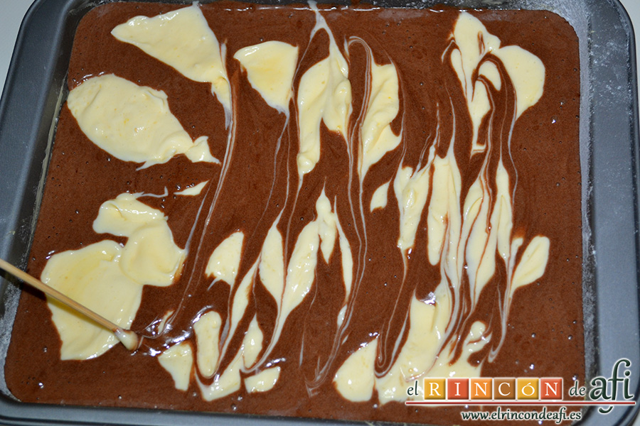 Brownie de chocolate con crema de queso, con ayuda de un pincho de madera moviéndolo de lado a lado