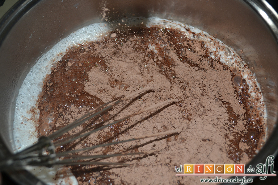 Natillas de chocolate, una vez que empieza a calentar la leche añadimos el cacao en polvo y batimos con unas varillas hasta que se disuelva.