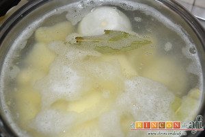 Papas revolconas con torreznos, en un caldero ponemos a cocer las papas chascadas, la cebolla, las hojas de laurel, la pastilla de caldo de carne cubiertas con agua
