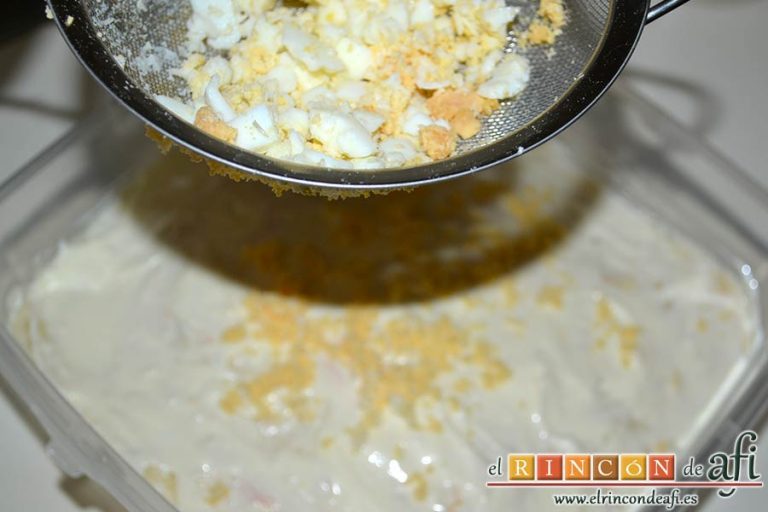 Ensaladilla con langostinos, cangrejo ruso, papas y huevos, pasar la ensaladilla a un recipiente y decorar con huevo muy picado