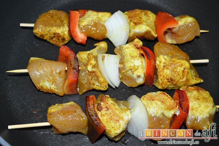 Brochetas de pechuga de pollo marinadas al curry con cebollas y pimientos, dar la vuelta a medida que queden dorados