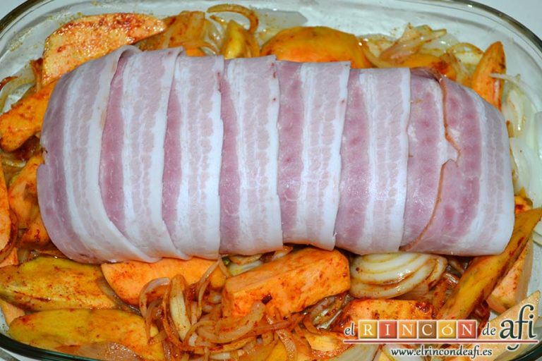 Lomo de cerdo al horno con cebollas y boniatos especiados, envolverlo con las tiras de bacon