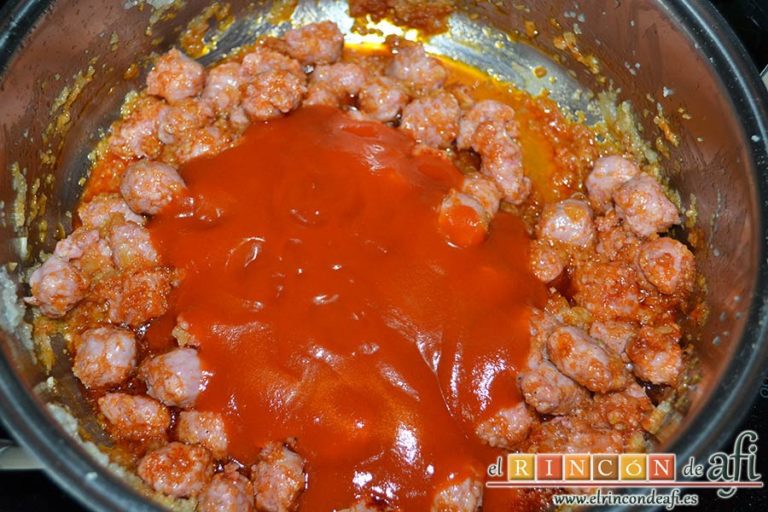 Espaguetis con salchichas y aceitunas, añadir el tomate frito y remover bien para integrar