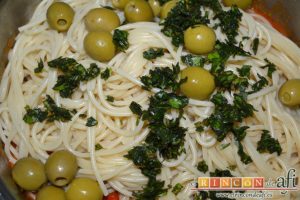 Espaguetis con salchichas y aceitunas, añadir la albahaca fresca picada y remover
