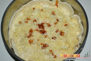 Pastel de tortillas con huevos, espolvorear con más queso rallado y picante