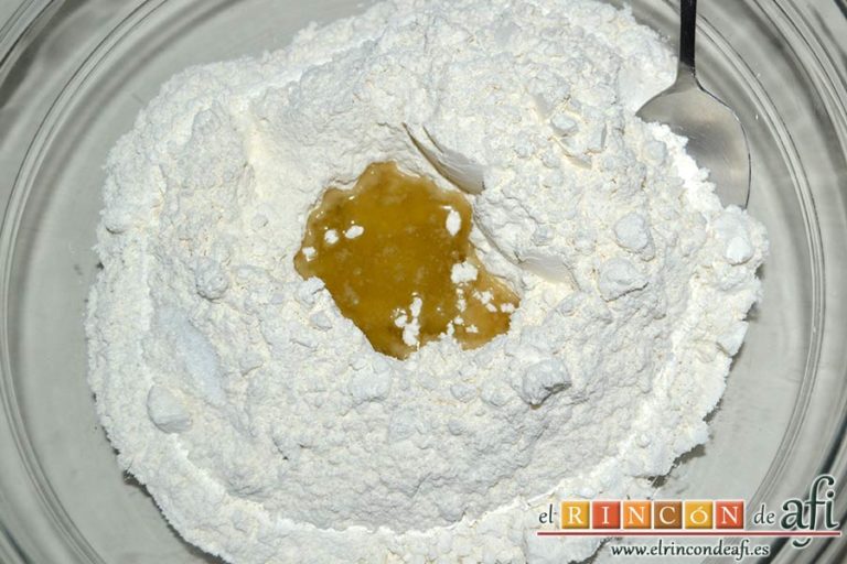 Empanada de langostinos y cebolla caramelizada, poner la harina en un bol, hacerle un agujero en el centro y añadir la sal y el aceite de oliva