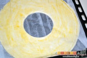 Roscón de hojaldre para Reyes, presionar para hacer un agujero y pintar con huevo batido