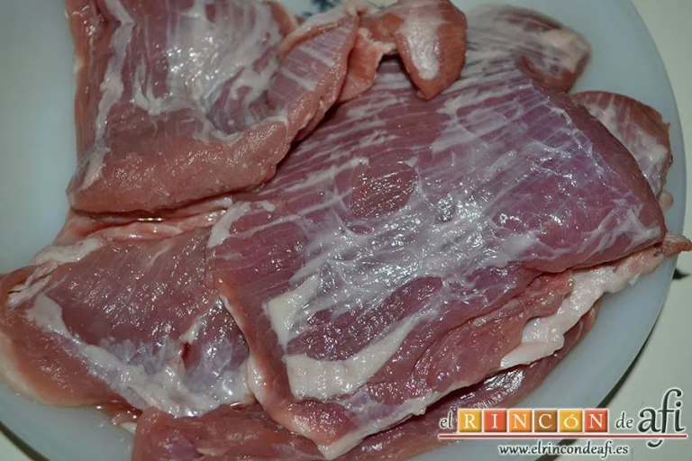 Secreto de cerdo al horno con papas panaderas y pimiento rojo, retirar exceso de grasa y cortar en trozos medianos