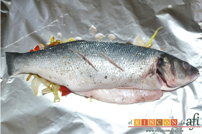 Papillote de lubina de ración con verduras, salpimentar la lubina por ambos lados y colocar sobre las verduras